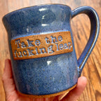 A blue  mug featuring the phrase "Take the fucking leap"