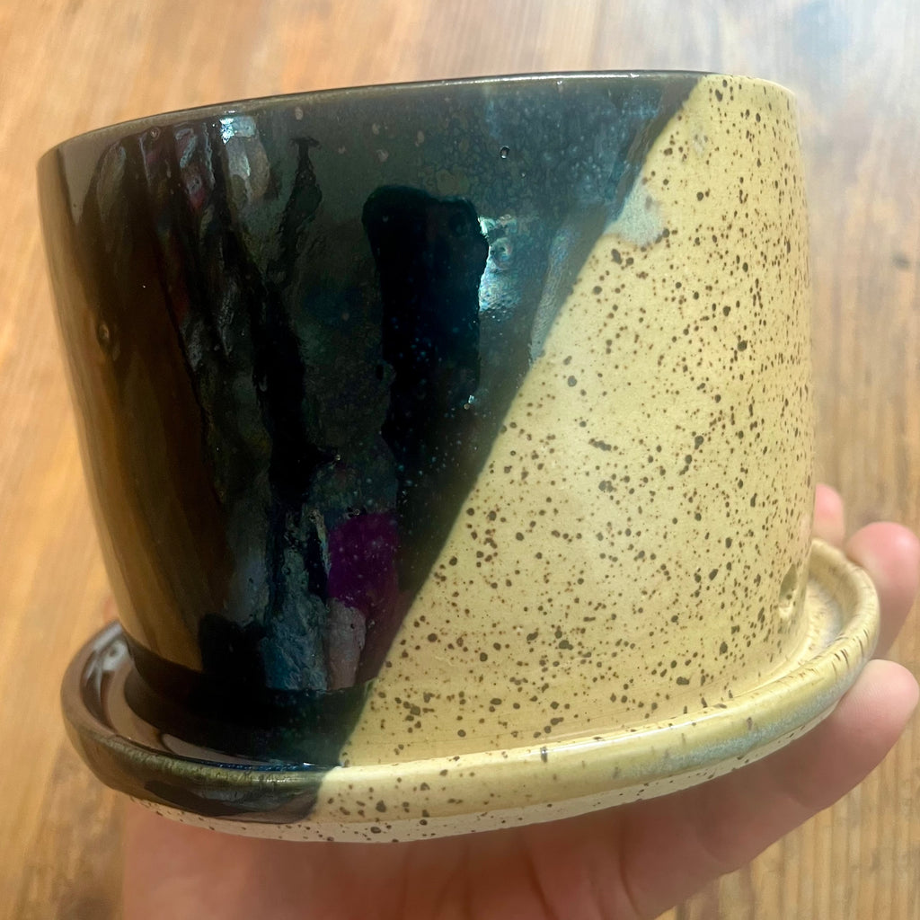 A planter with one half glazed in metallic black and one half glazed in clear