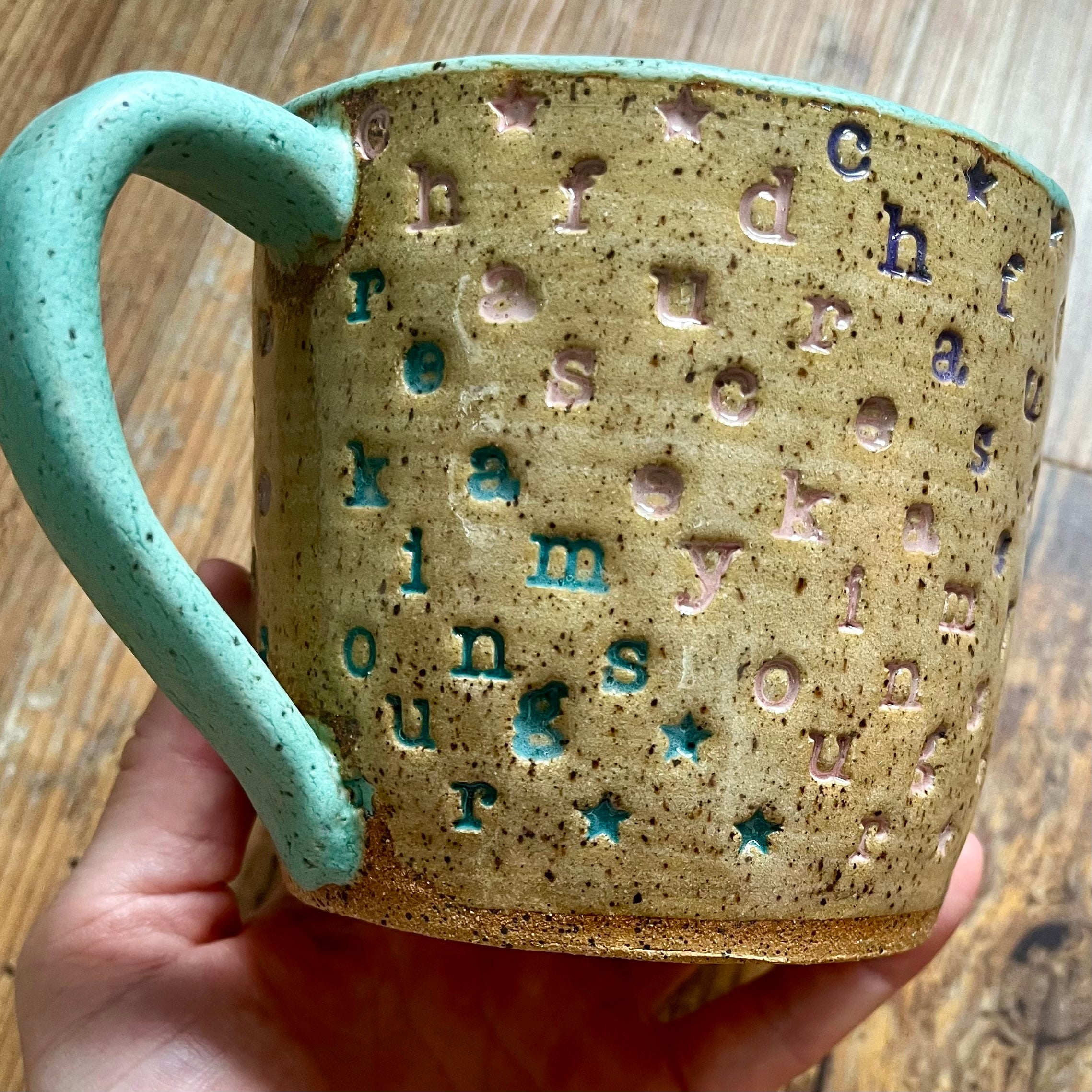 a mug with "chase your fucking dreams" stamped in diagonal stripes with a seaglass colored handle