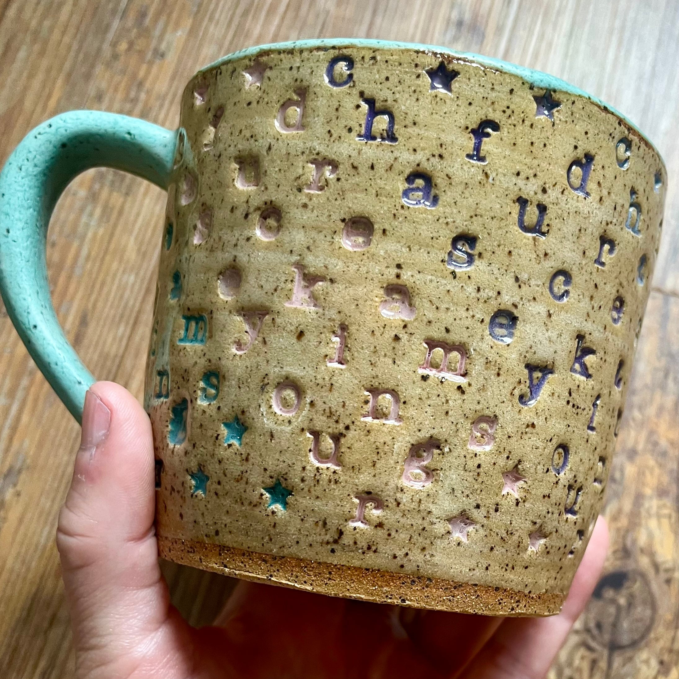 a mug with "chase your fucking dreams" stamped in diagonal stripes with a seaglass colored handle