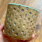 A mug with "do it scared" stamped in diagonal rainbow-colored stripes with a seaglass colored handle