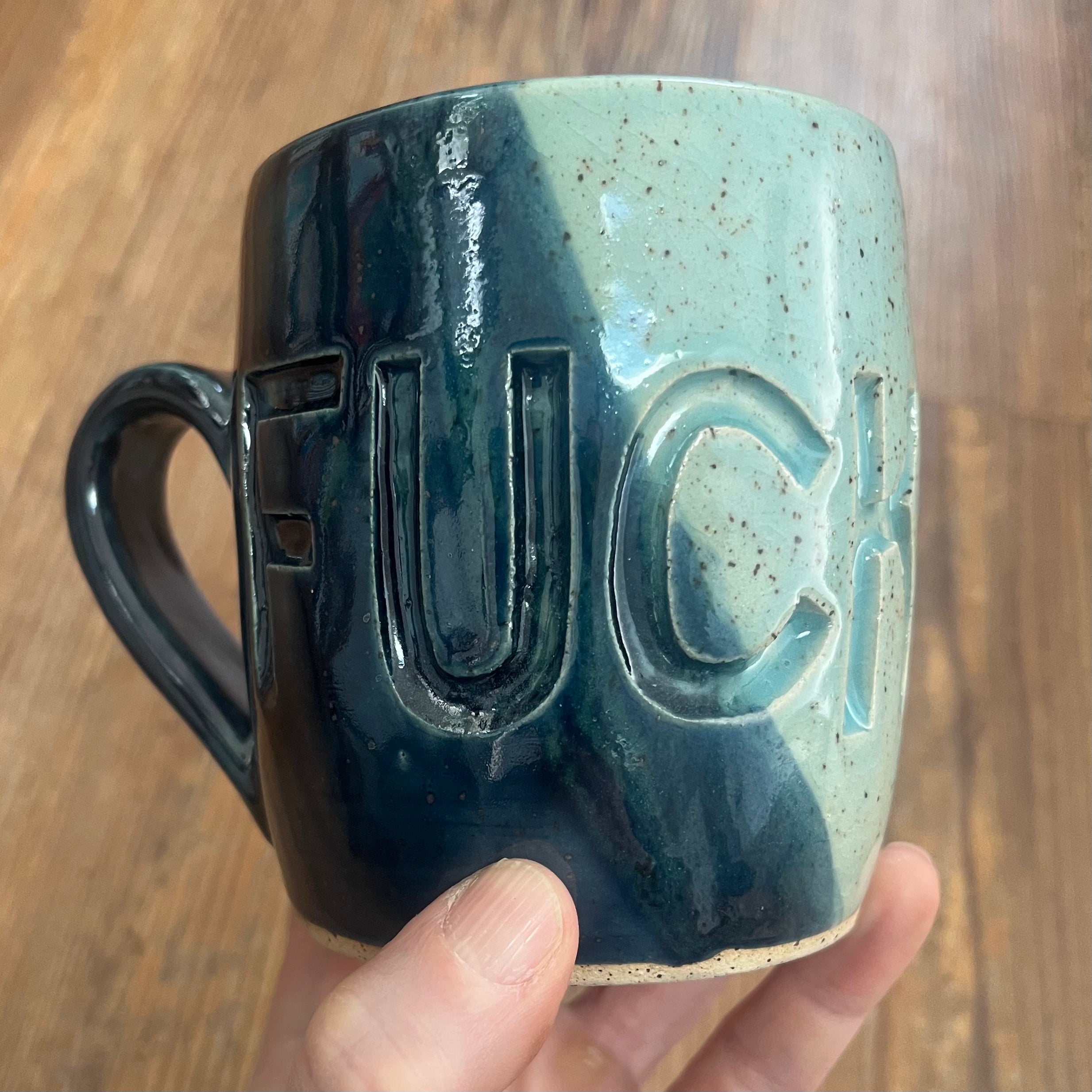 Hand holding a dark and light blue mug with fuck ice carved into it