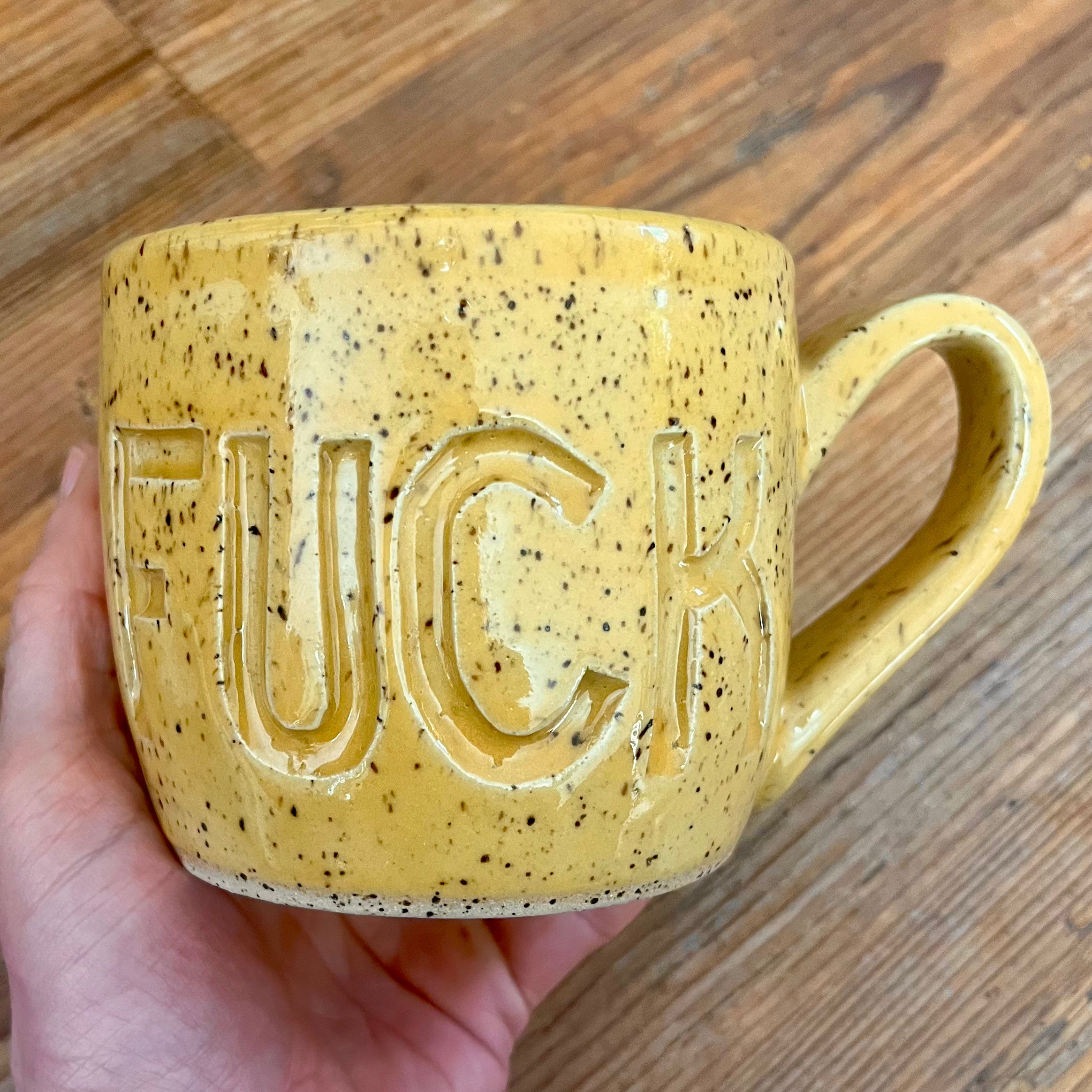 Yellow mug with fuck carved into it
