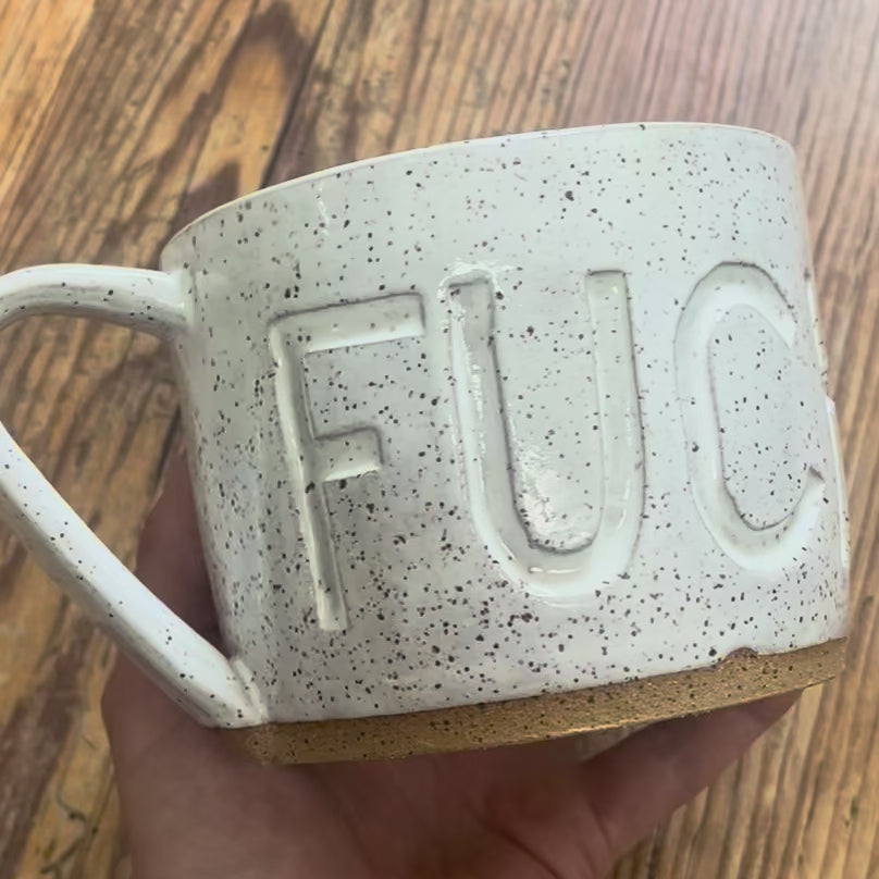 A video rotating around a white speckled mug with the word FUCK carved into it