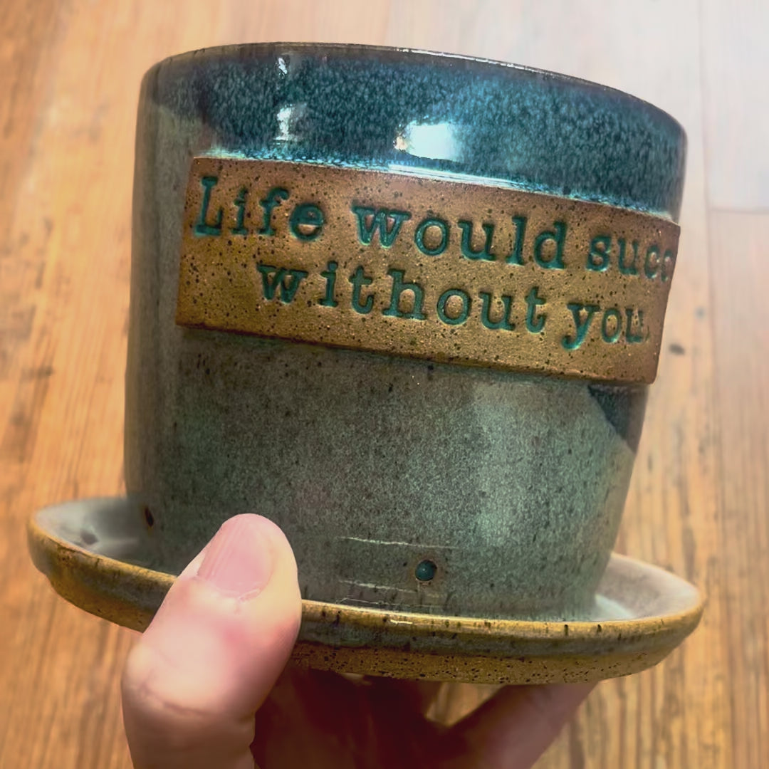 A video of a planter with the phrase "Life would succ without you"