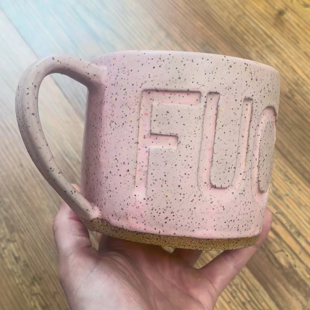 A video rotating around a pink mug with the word FUCK carved into it