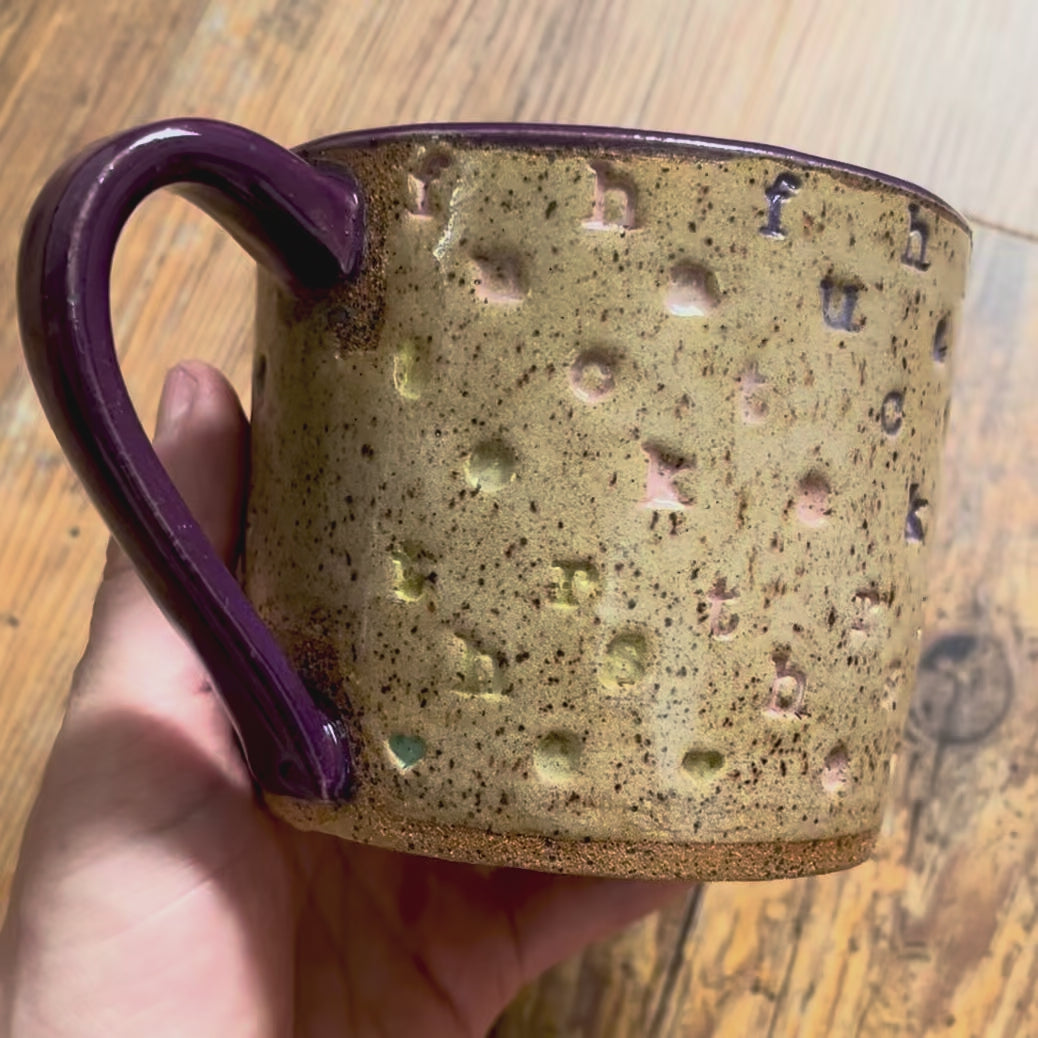 A video rotating around a mug with f*ck the haters stamped in diagonal stripes with a purple handle