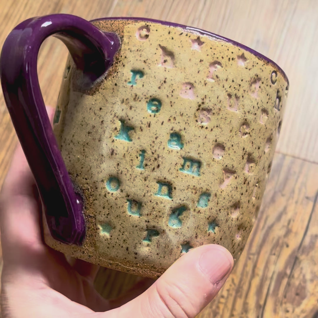 A video rotating around a mug with "chase your fucking dreams" stamped in diagonal stripes with a purple handle